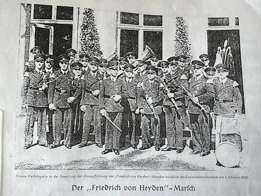 Kopie eines Zeitungsartikels von 1936 mit Titel "Der Friedrich von Heyden-Marsch" und einem abgedruckten Foto einer Musikkapelle mit zwei Dutzend uniformierten Musikern samt ihrer Blas- und Schlag-Instrumente