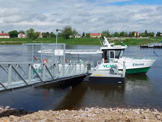 Foto: Eine kleine Personenfähre mit der Beschriftung "Elbnixe" liegt in einem Fluss an einem Anleger