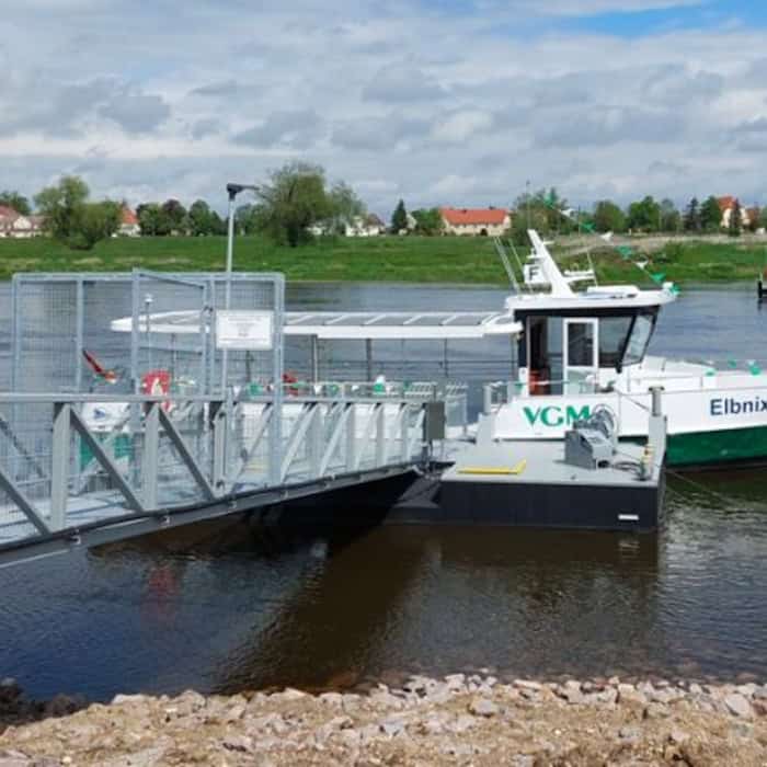 Foto: Eine kleine Personenfähre mit der Beschriftung "Elbnixe" liegt in einem Fluss an einem Anleger