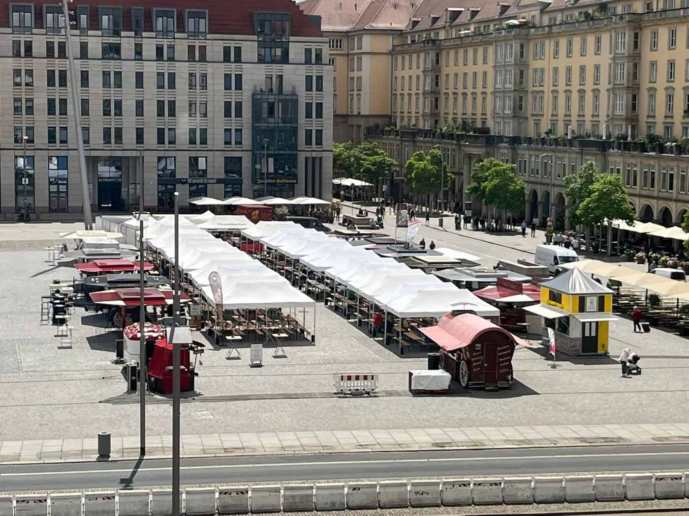 Blick von oben auf den Dresdner Altmarkt mit langen Reihen weißer Marktzelte und Verkaufsständen. Im Hintergrund befinden sich helle, mehrstöckige Gebäude der Innenstadt an einem sonnigen Tag.
