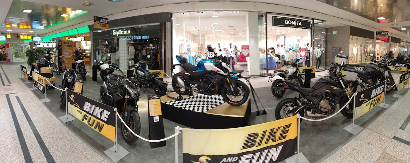 Blick entlang eines Gangs in einem Shopping-Center, in der Mitte zahlreiche ausgestellte Motorräder, Absperrung mit der Aufschrift "Bike and Fun"