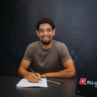 Ben Bobzien sitzt an einem Tisch und unterschreibt seinen Vertrag bei Dynamo Dresden. Vor ihm liegen die Vertragsunterlagen, während er ein schwarzes T-Shirt trägt.