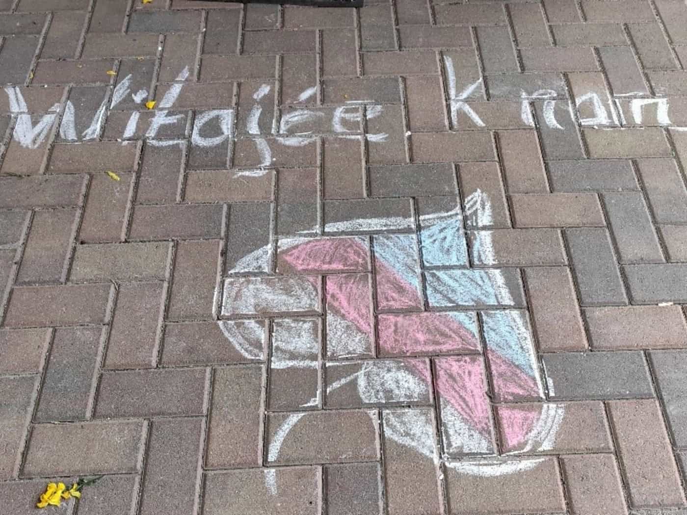 Auf einem Fußweg stehen mit Kreide die Worte „Witajće k nam“, darunter ein gezeichnetes Lindenblatt