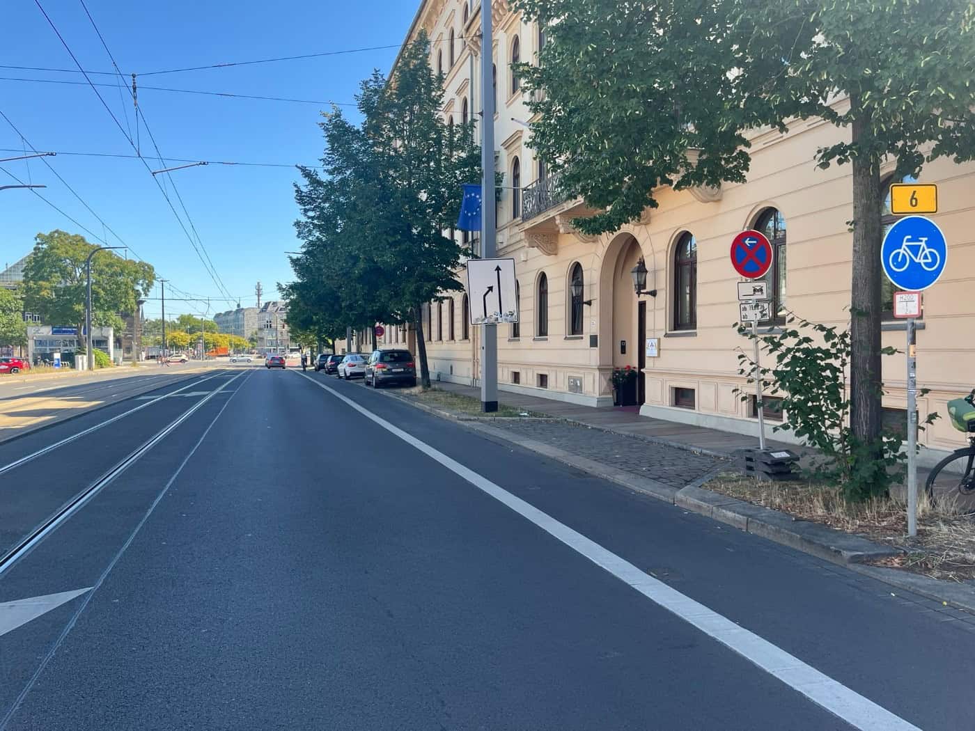 Blick auf die Antonstraße in Dresden mit Fahrbahn, Straßenbahnschienen und Fahrradweg. Auf der rechten Seite stehen historische Gebäude, Straßenbäume sowie Verkehrsschilder, darunter ein blaues Radweg-Schild.