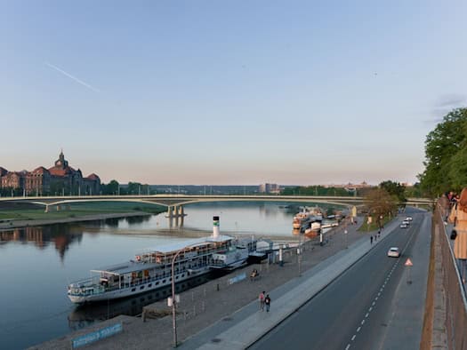 Visualisierung der geplanten Carolabrücke in Dresden, gesehen von der Brühlschen Terrasse. Ein Raddampfer liegt am Elbufer an, rechts verläuft die Straße Terrassenufer und im Hintergrund steht das Finanzministerium.