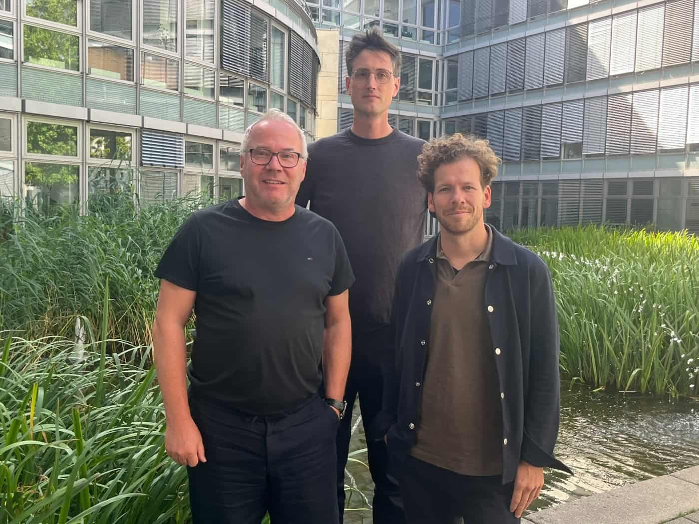 Stefan Burgard, Tobias Mansperger und Frank Großkopf (v. l.) von der Planergemeinschaft LAP und Querfeldeins stehen vor einer Glasfassade im Außenbereich und blicken in die Kamera.