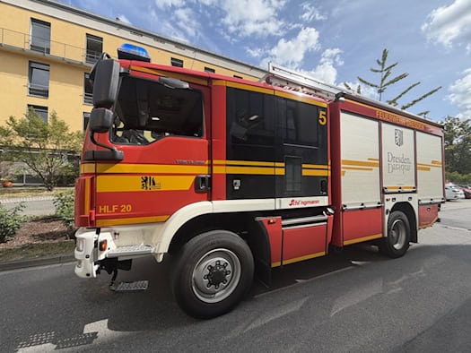 Ein rot-gelbes Einsatzfahrzeug der Feuerwehr Dresden (HLF 20) steht vor einem gelben Gebäude des Städtischen Klinikums Friedrichstadt auf dem Gelände.