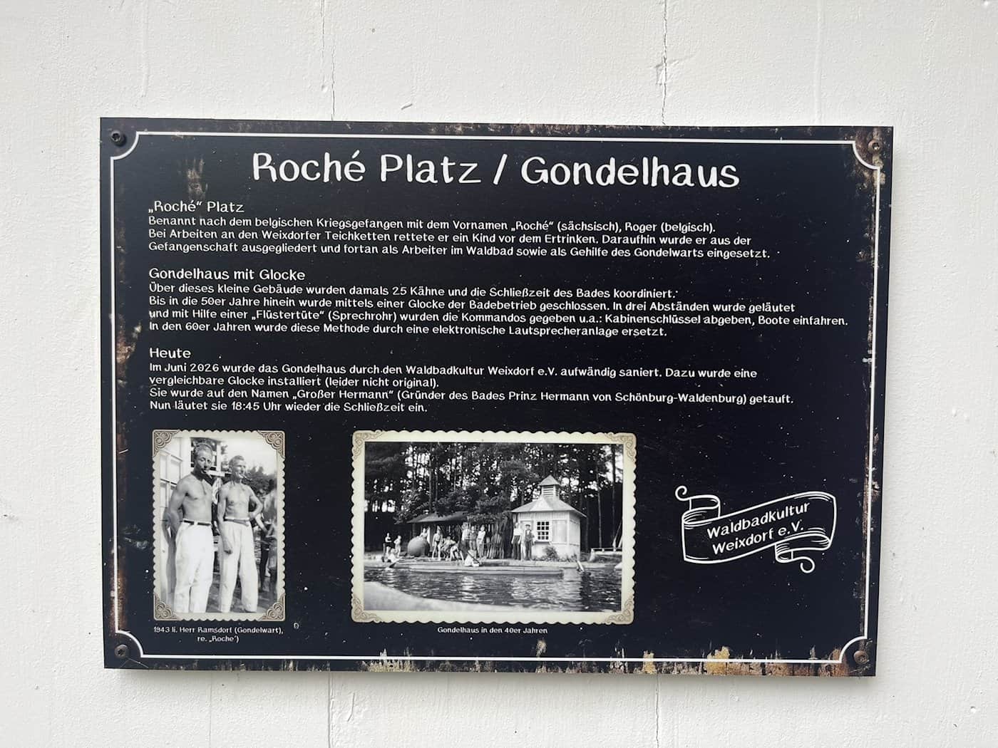 Schwarze Infotafel an einer weißen Wand mit der Aufschrift „Roché Platz / Gondelhaus“. Der Text erklärt die Geschichte des Waldbads Weixdorf, ergänzt durch zwei historische Schwarz-Weiß-Fotos aus den 1940er-Jahren und das Logo des Vereins Waldbadkultur Weixdorf e.V.