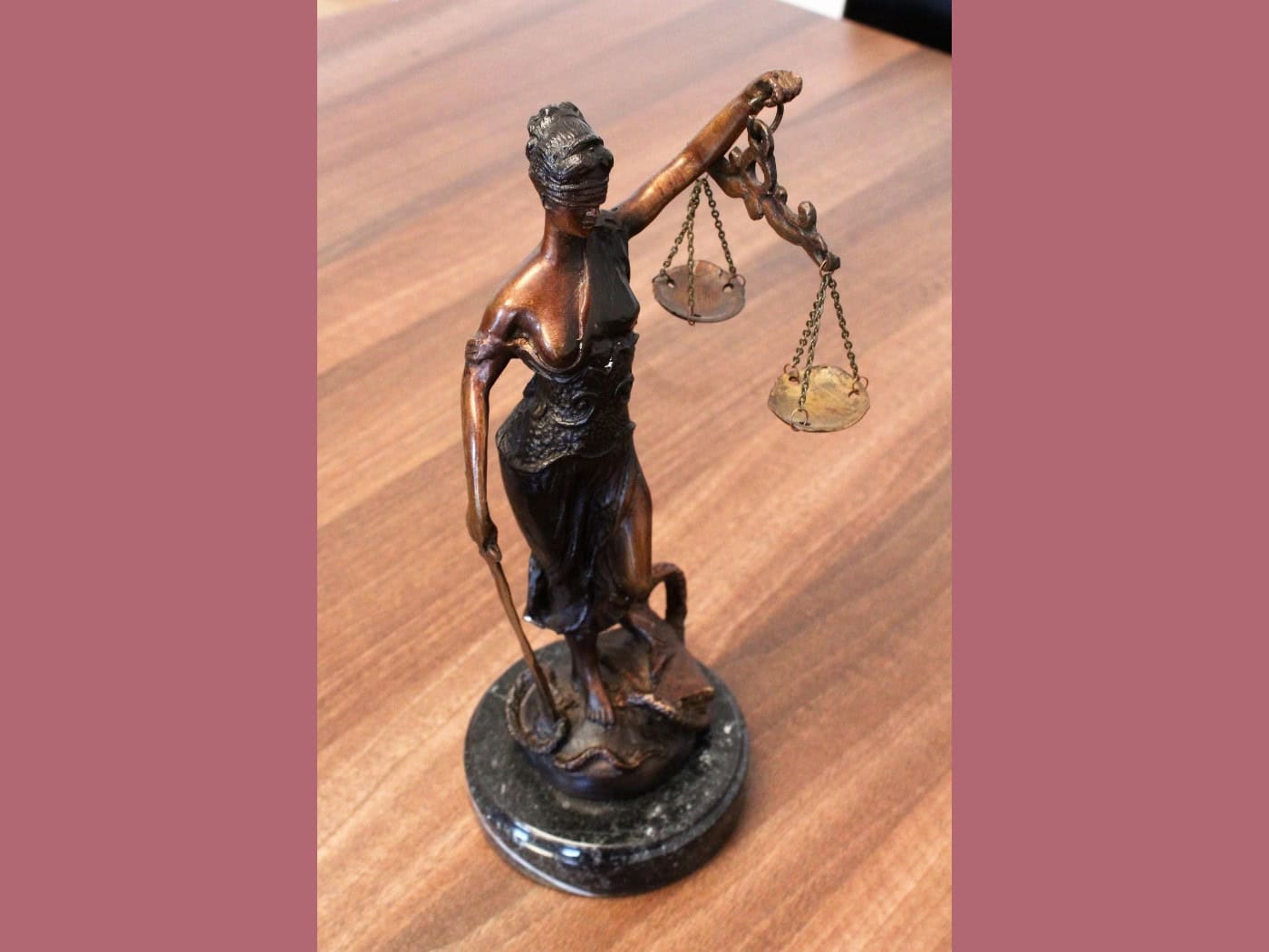 Eine kleine Bronze-Statue der Justitia mit Augenbinde, Waage und Schwert steht auf einer hölzernen Tischoberfläche. Das Symbolbild steht für die Anklage der Staatsanwaltschaft Dresden.