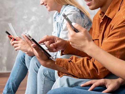 Drei Personen nutzen nebeneinander Tablet und Smartphones im Alltag