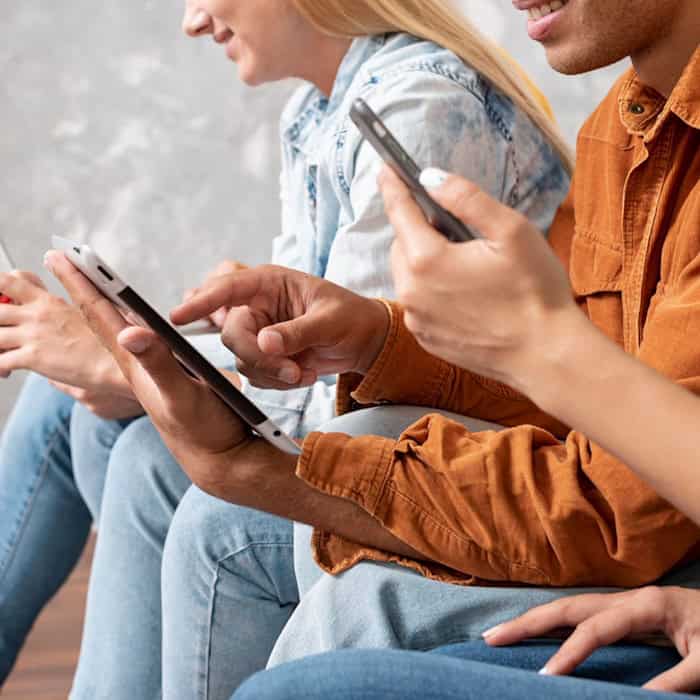 Drei Personen nutzen nebeneinander Tablet und Smartphones im Alltag