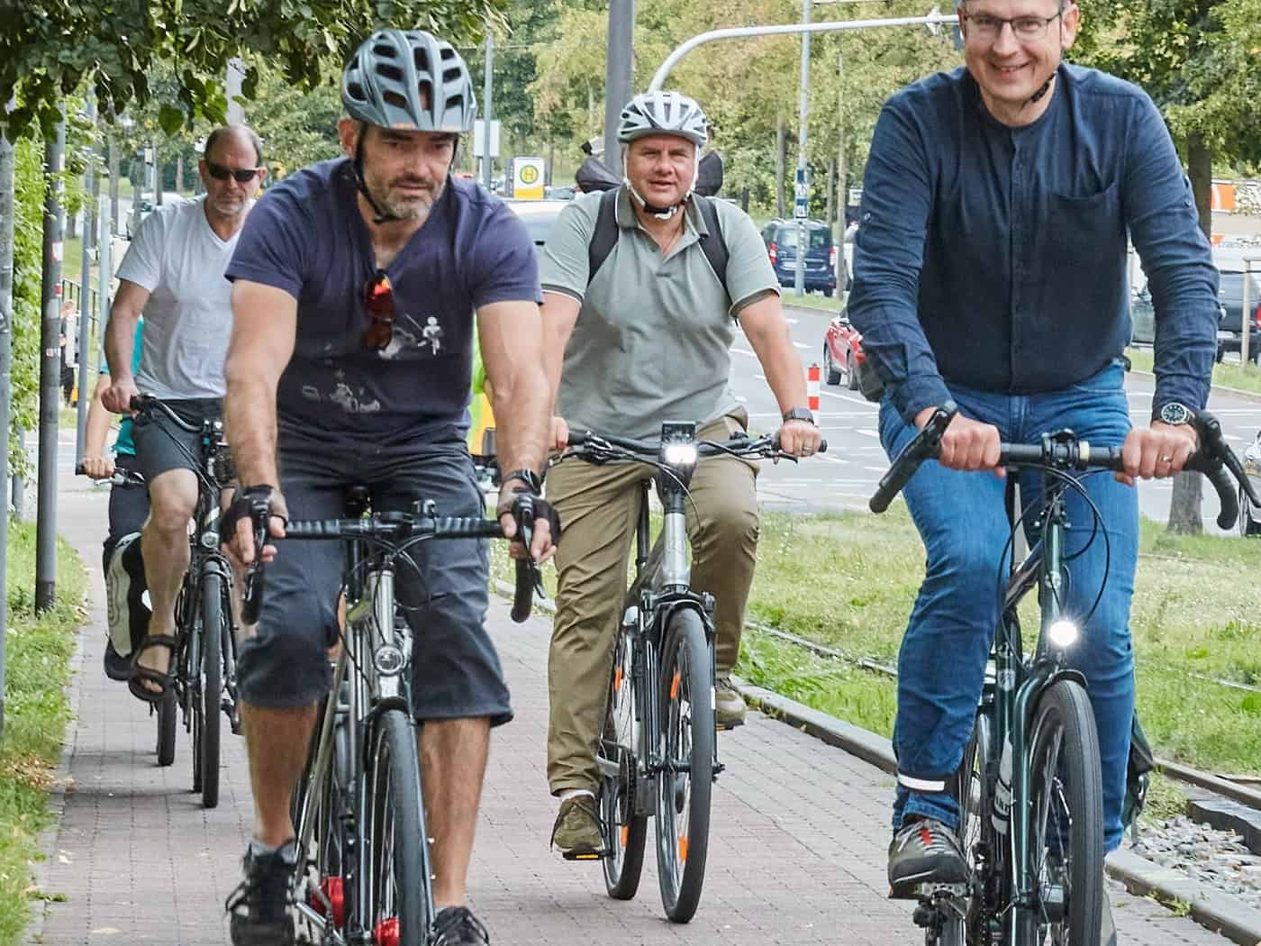 Dresdens Oberbürgermeister Dirk Hilbert radelt auf einem Fahrrad zusammen mit einer Gruppe von ADFC-Mitgliedern durch das Stadtgebiet. Die Radfahrer fahren auf einem gepflasterten Radweg im Stadtverkehr.