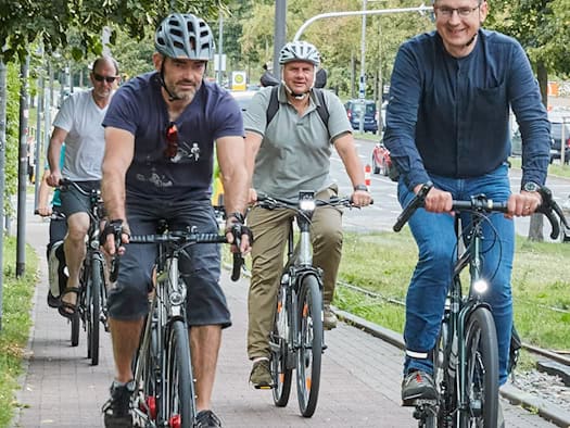 Dresdens Oberbürgermeister Dirk Hilbert radelt auf einem Fahrrad zusammen mit einer Gruppe von ADFC-Mitgliedern durch das Stadtgebiet. Die Radfahrer fahren auf einem gepflasterten Radweg im Stadtverkehr.