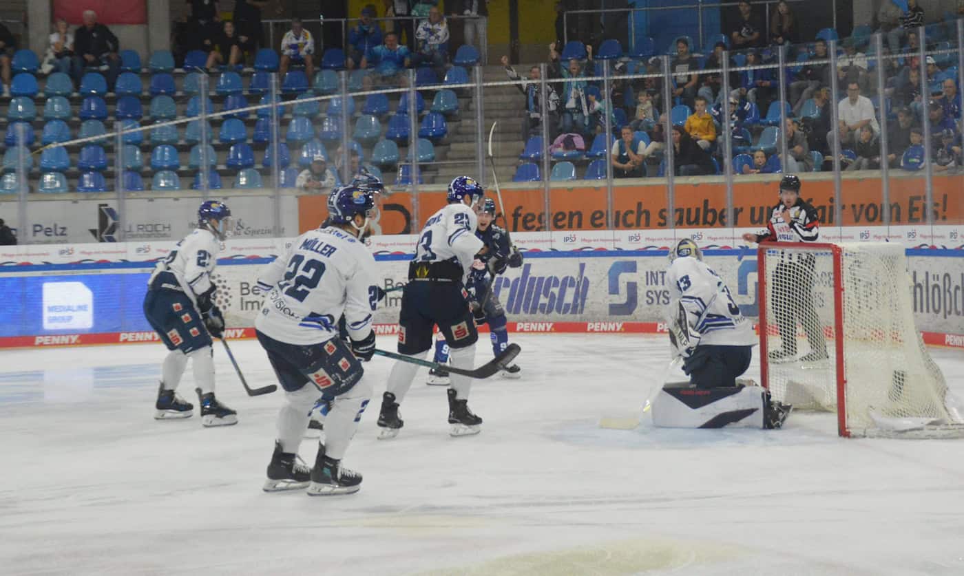 Dane Fox trifft zum 2:0 für die Dresdner Eislöwen gegen Kassel Huskies Eishockeyszene vor dem Tor: Eislöwen-Spieler im dunklen Trikot greifen den Goalie der Kassel Huskies im weißen Trikot an, der schützend auf dem Eis kniet.