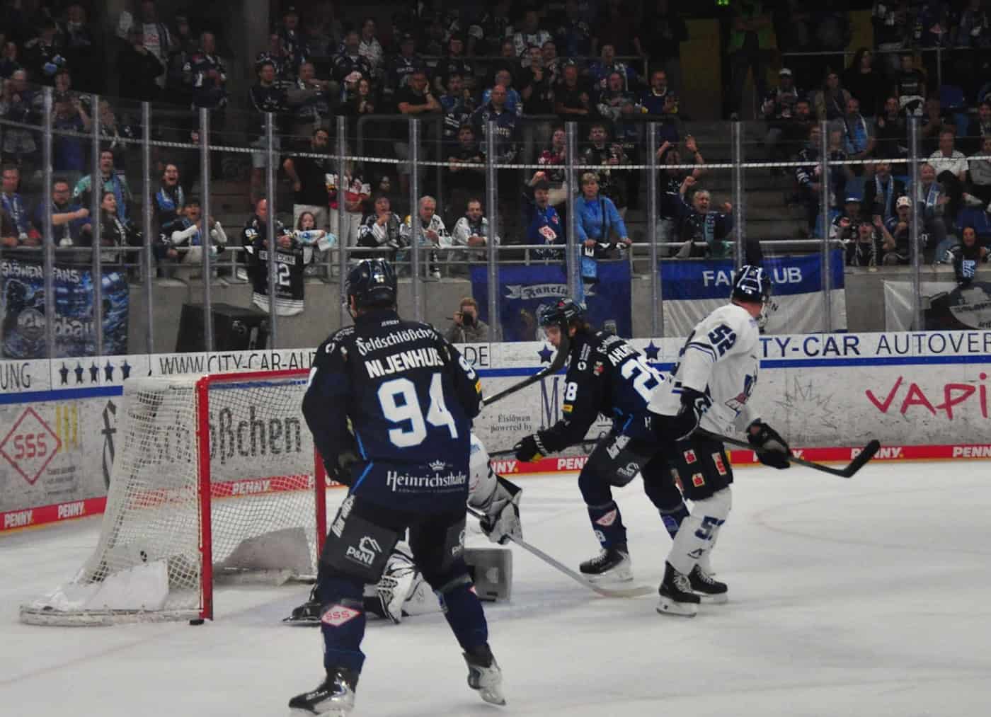 Jan Nijenhuis trifft im Powerplay zum 4:1 für die Dresdner Eislöwen gegen Kassel Rückansicht von Eislöwen-Spieler Jan Nijenhuis (Rückennummer 94) vor dem gegnerischen Torraum. Im Hintergrund jubeln Fans hinter der Glasbande der Eisarena.