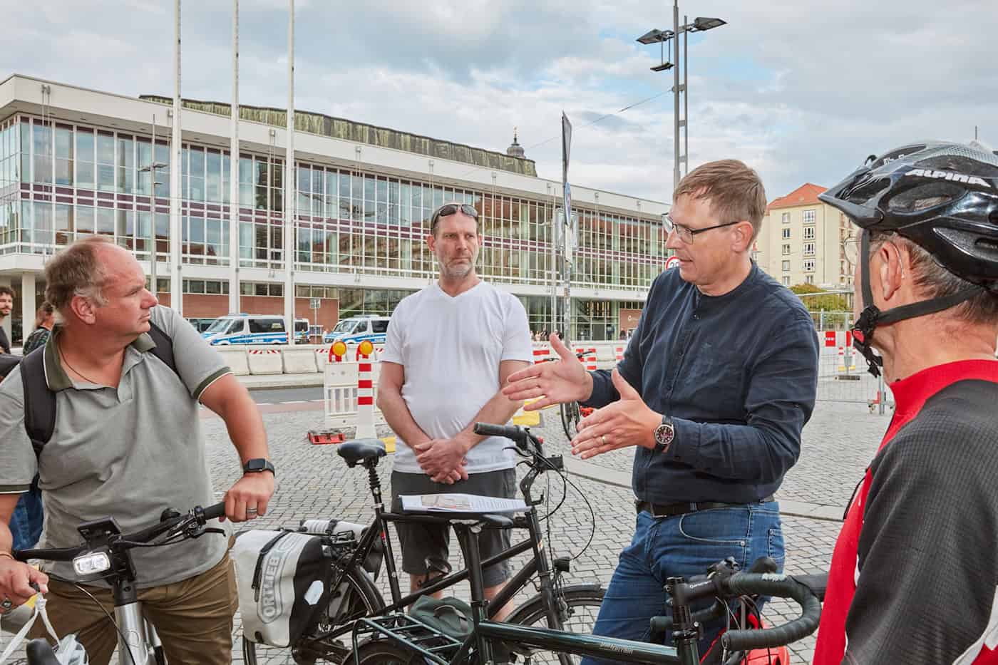 Diskussion zum Radverkehr auf dem Dresdner Altmarkt mit OB Dirk Hilbert und ADFC Gruppe von Radfahrern, darunter Oberbürgermeister Dirk Hilbert, steht ohne Helm im Gespräch auf dem Dresdner Altmarkt neben ihren Fahrrädern. Im Hintergrund erstreckt sich die Fassade des Kulturpalastes.