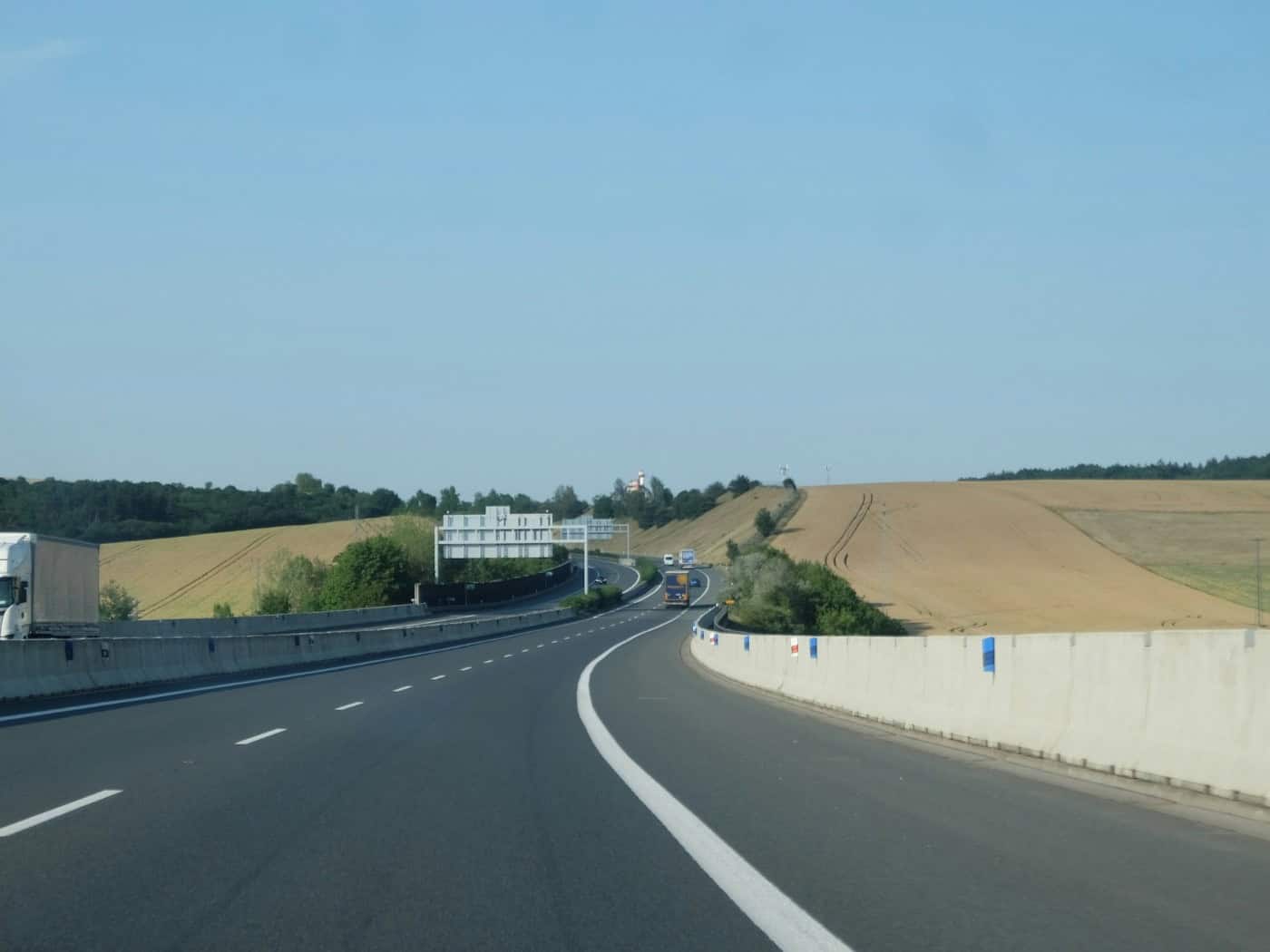 Autobahn mit Fahrzeugen zwischen Feldern unter blauem Himmel