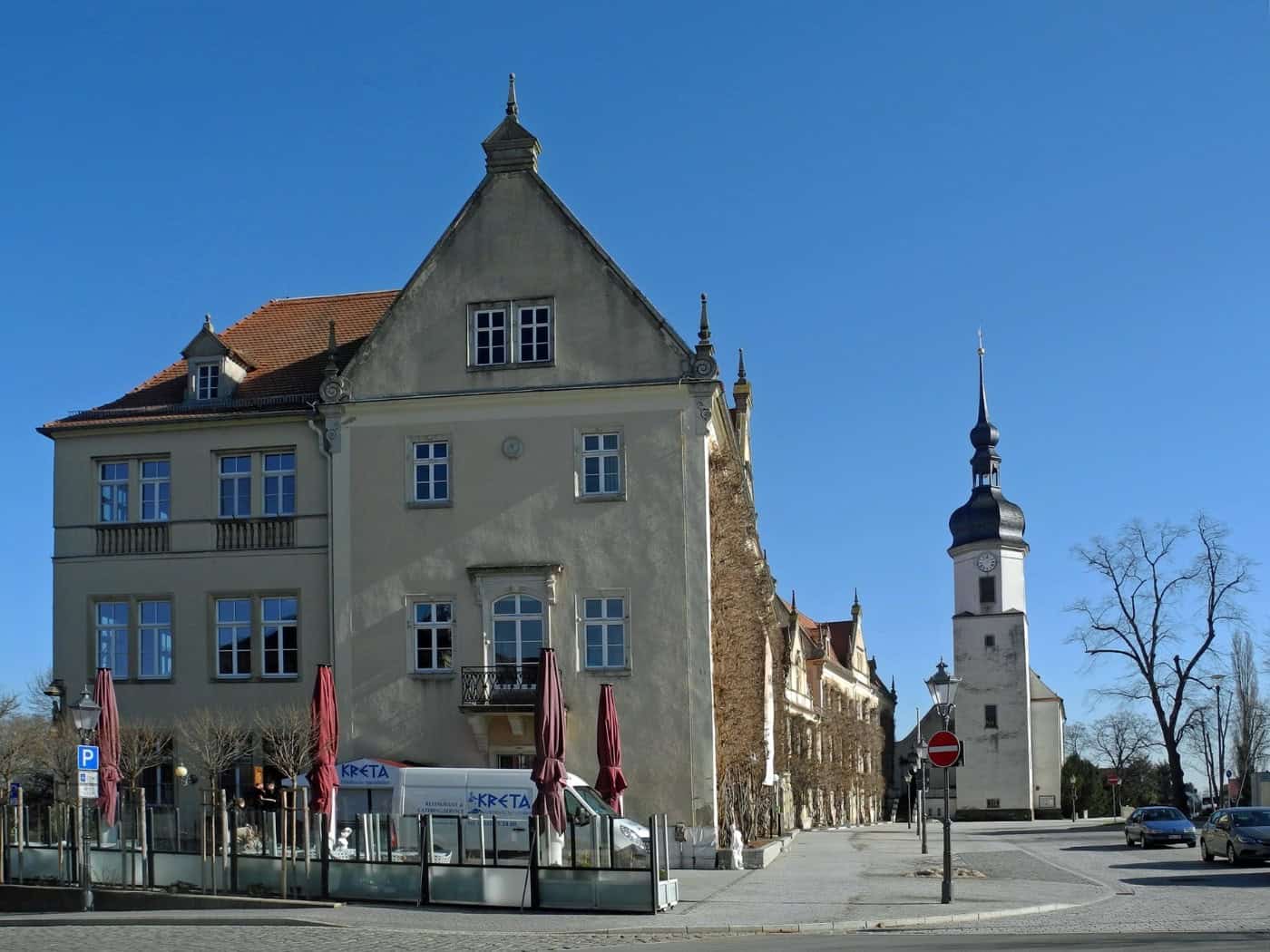 Rathaus Riesa, ein heller historischer Bau mit Giebel, rechts der Turm der Klosterkirche, davor eine Straße