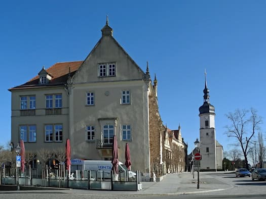 Rathaus Riesa, ein heller historischer Bau mit Giebel, rechts der Turm der Klosterkirche, davor eine Straße