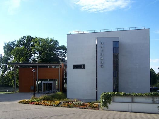 Modernes weißes Rathausgebäude in Coswig mit senkrechtem Schriftzug Rathaus, davor ein Blumenbeet