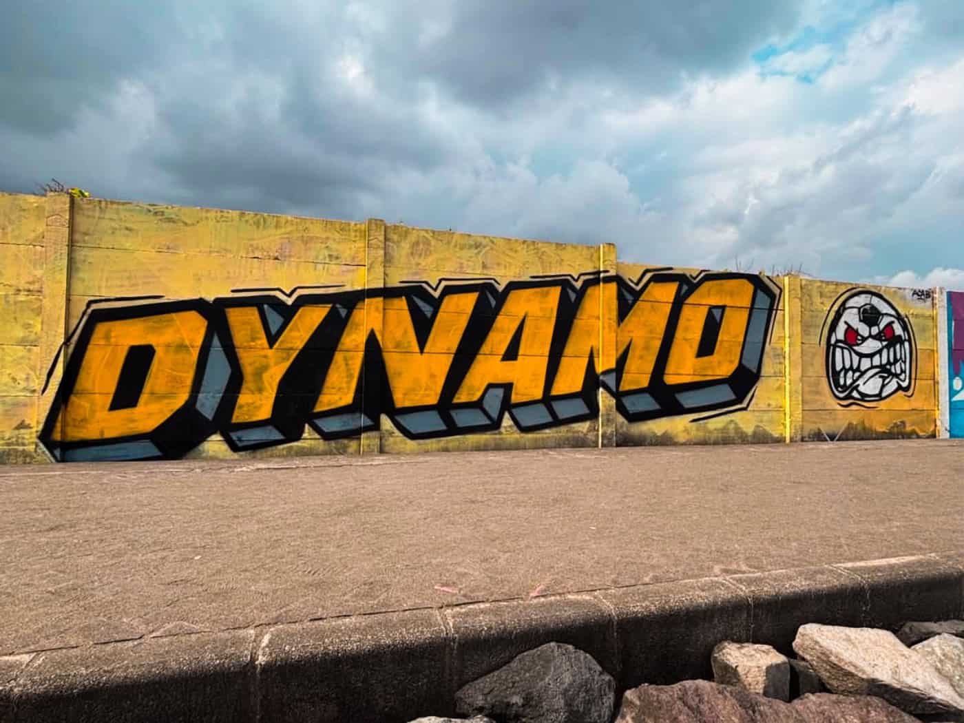Dynamo-Graffiti mit gelbem Schriftzug und Symbol der Ultras Dynamo an einer Mauer auf Bali.