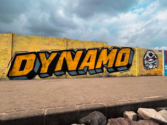 Dynamo-Graffiti mit gelbem Schriftzug und Symbol der Ultras Dynamo an einer Mauer auf Bali.