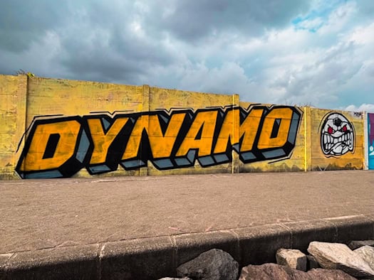 Dynamo-Graffiti mit gelbem Schriftzug und Symbol der Ultras Dynamo an einer Mauer auf Bali.