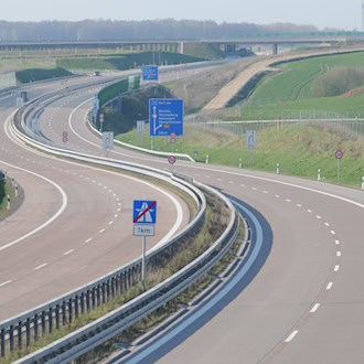 Blick auf die geschwungene A72 bei Rochlitz mit getrennten Fahrbahnen, Leitplanken und blauen Wegweisern, aufgenommen 2013.