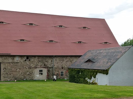 Historisches Klostergebäude mit rotem Ziegeldach im Klosterpark Altzella auf einer grünen Wiese