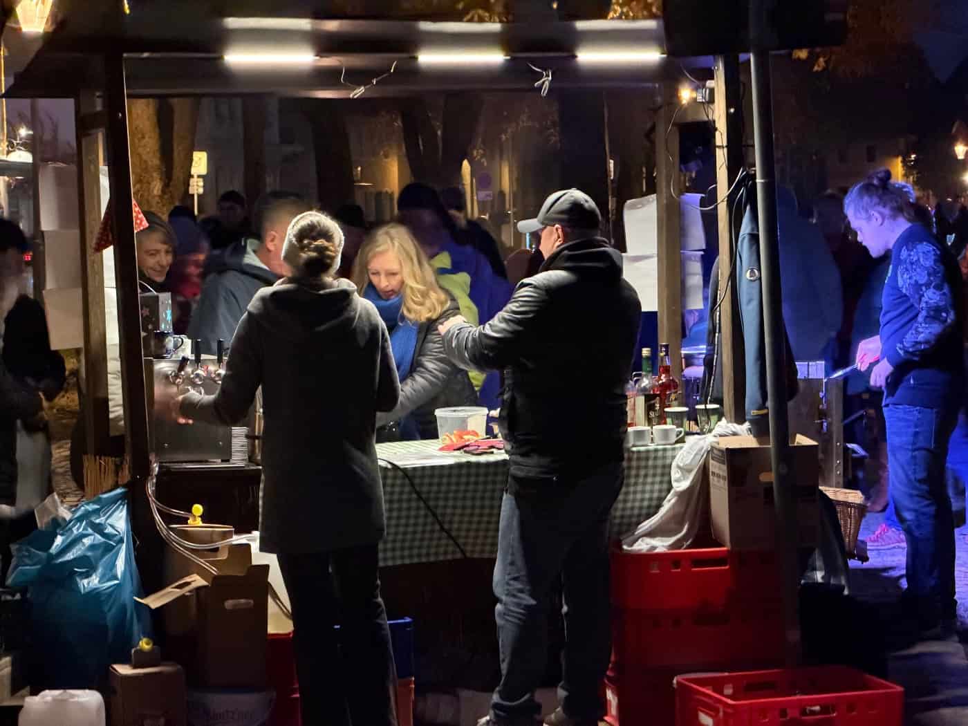 Gäste an einem beleuchteten Glühweinstand am Abend beim Radebeuler Anglühen