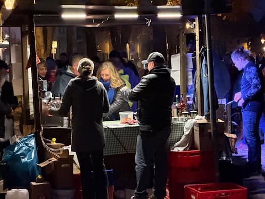 Gäste an einem beleuchteten Glühweinstand am Abend beim Radebeuler Anglühen
