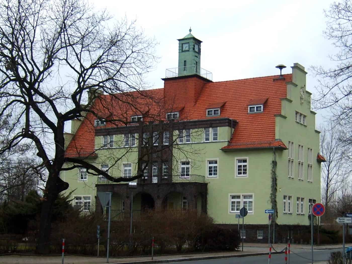 Grün gestrichenes Rathaus von Gröditz mit rotem Ziegeldach und Uhrturm