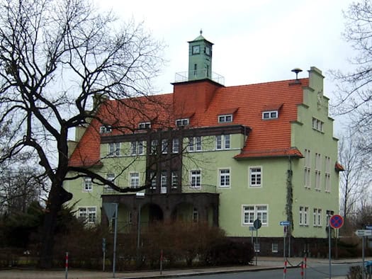 Grün gestrichenes Rathaus von Gröditz mit rotem Ziegeldach und Uhrturm