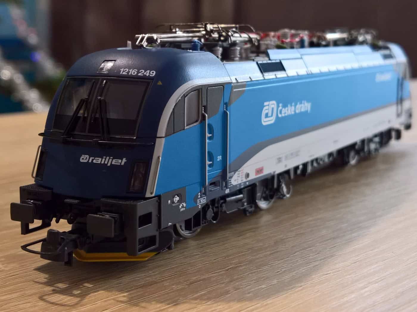 Symbolbild: Ein blau-graues Modell einer ČD-Elektrolokomotive der Tschechischen Bahnen mit der Aufschrift „Railjet“ steht auf einem Holztiisch vor unscharfem Hintergrund.