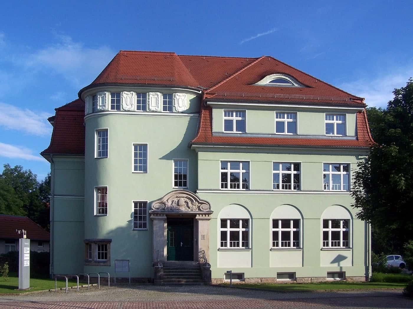 Hellgrünes Gebäude mit rotem Dach und Rundturm in der Karrasstraße 3 in Coswig