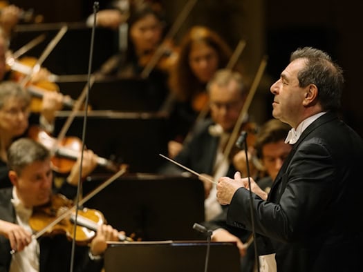 Chefdirigent Daniele Gatti im Profil im Frack mit Taktstock vor den Streichern der Sächsischen Staatskapelle Dresden während eines Konzerts in der Semperoper.