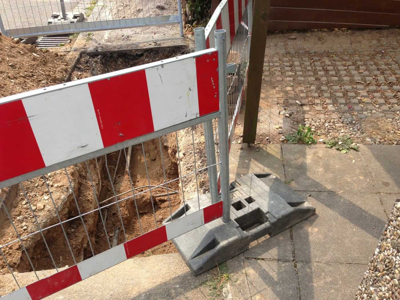 Blick auf das Schulgebäude der Freien Evangelischen Schule Dresden in der Aussiger Straße in Tolkewitz. Im Vordergrund sind Gehweg, Fahrbahn und geparkte Fahrzeuge zu sehen, im Hintergrund ein Schulschild mit Logo sowie Bäume.