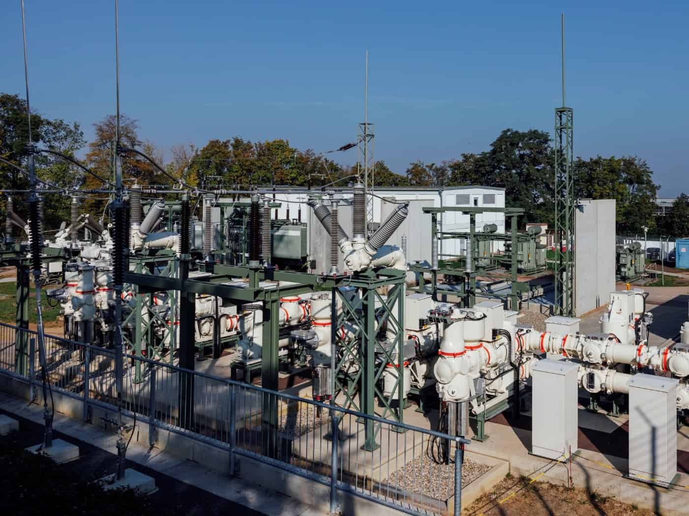 Außenanlage des Umspannwerks Räcknitz in Dresden mit silbrigen Schaltanlagen, hochragenden Isolatoren und Transformatoren auf einem eingefassten Areal vor blauem Himmel.