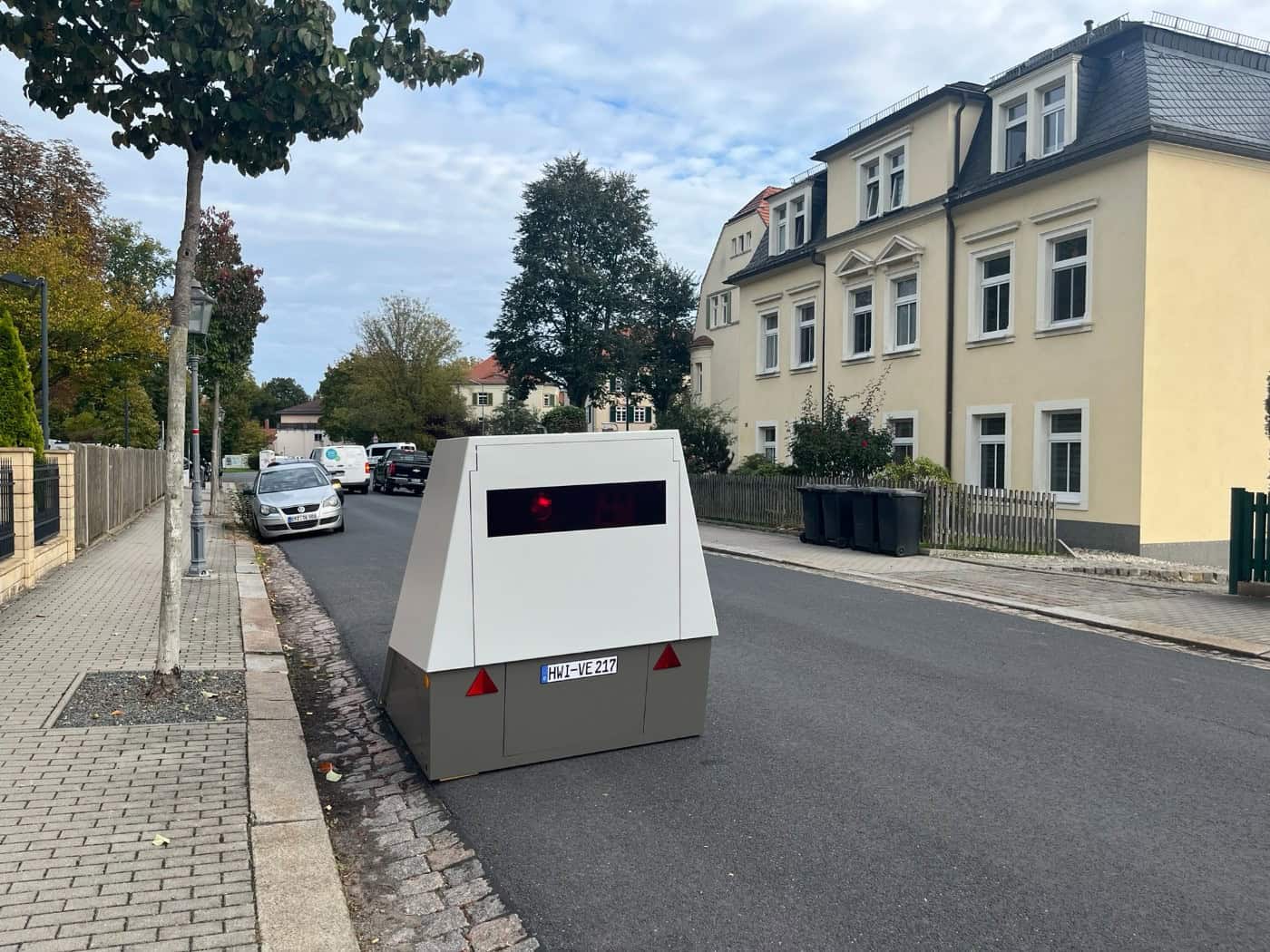 Ein weiß-grauer Blitzer-Messanhänger mit dem Nummernschild HWI-VE 217 steht am Rand der Schützenhofstraße in Dresden vor Wohnhäusern und kontrolliert die Tempo-30-Zone.