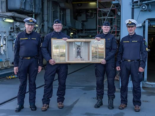 Vier Marinesoldaten an Deck der Fregatte Sachsen halten die Plakette des Barbarapreises