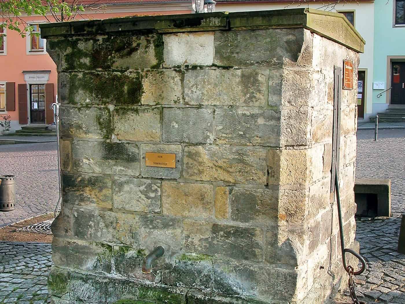 Marktbrunnen auf dem Marktplatz von Strehla mit historischen Häusern im Hintergrund