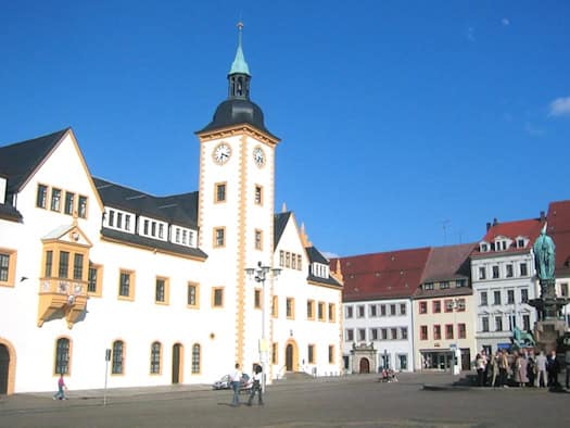 Weißes Rathaus mit Uhrturm am Obermarkt in Freiberg bei blauem Himmel