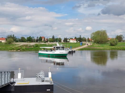 Weiße Elektrofähre „Elbnixe“ auf der Elbe, gesehen von der Fährstelle Strehla