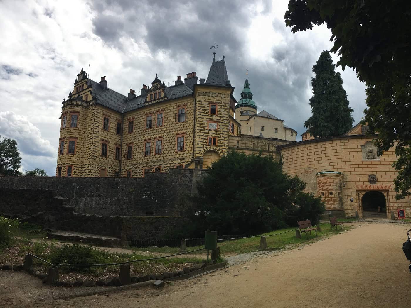 Schloss Frýdlant mit reich verzierter Fassade, mehreren Türmen und einem steinernen Eingangstor.