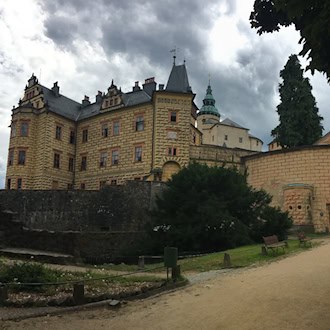 Schloss Frýdlant mit reich verzierter Fassade, mehreren Türmen und einem steinernen Eingangstor.