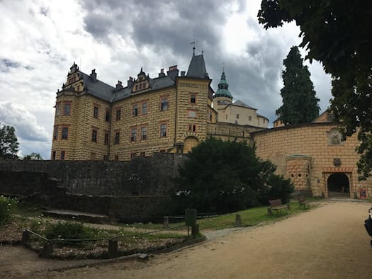 Schloss Frýdlant mit reich verzierter Fassade, mehreren Türmen und einem steinernen Eingangstor.