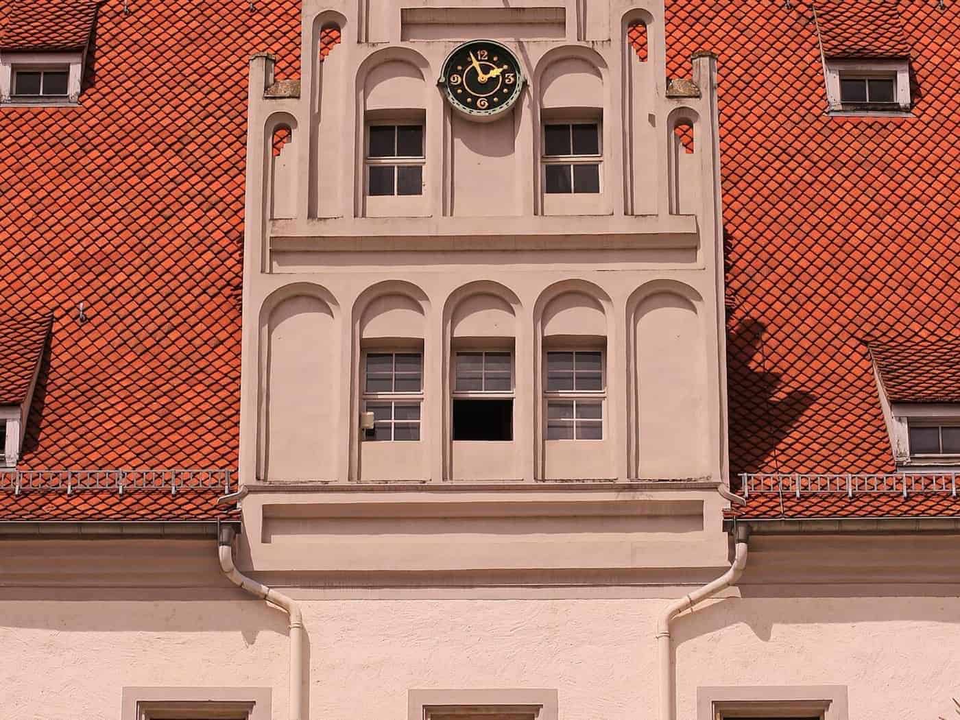 Ziergiebel mit Uhr am Meißner Rathaus, darunter Fenster mit roten Blumenkästen