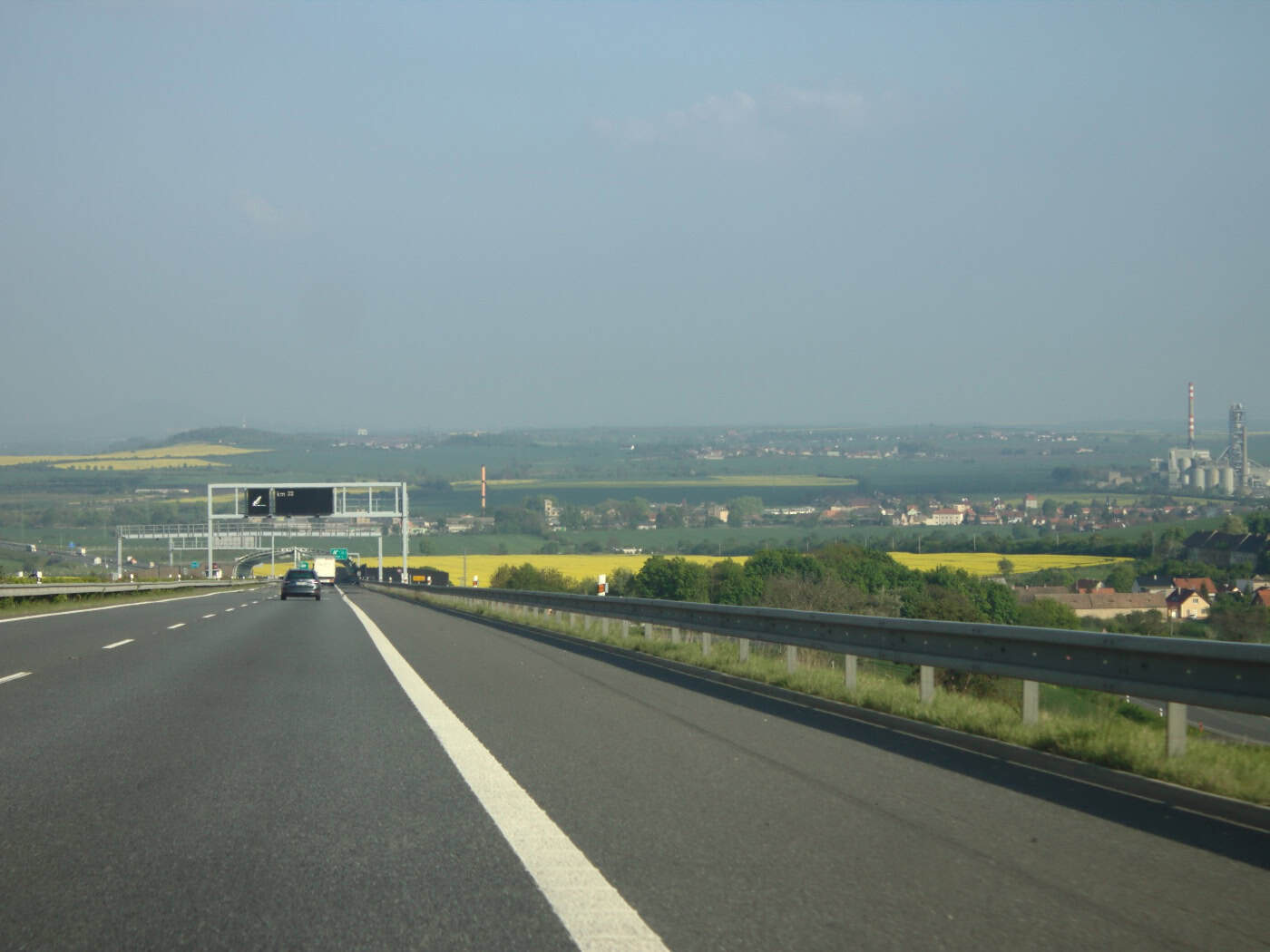 Fahrzeuge auf der Autobahn D8 bei Lovosice mit Feldern und Gebäuden im Hintergrund.