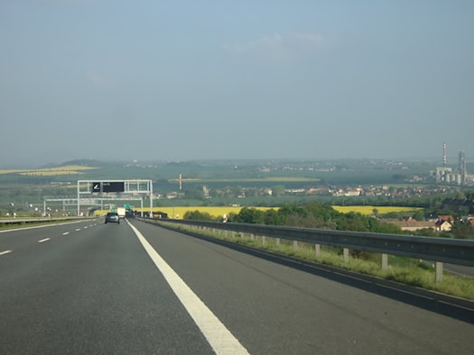 Fahrzeuge auf der Autobahn D8 bei Lovosice mit Feldern und Gebäuden im Hintergrund.