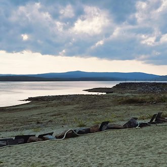 Freigelegter steiniger Uferbereich am Lipno-Stausee bei Dolní Vltavice unter bewölktem Himmel.